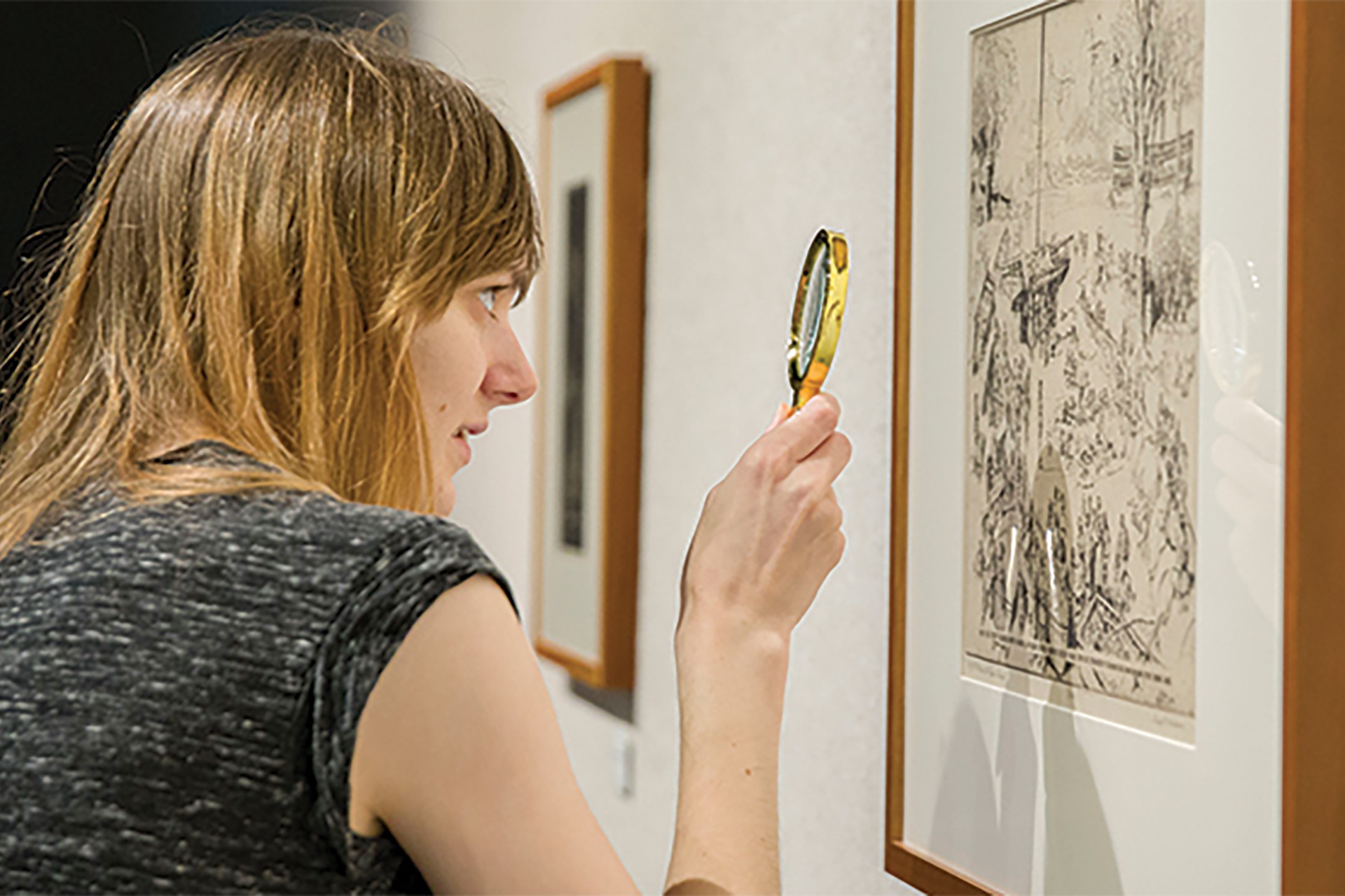 Student viewing etched artwork with magnifying glass