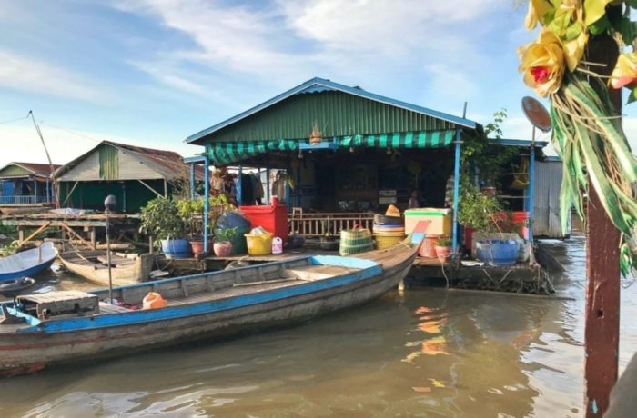 A boat in front of a floating house.