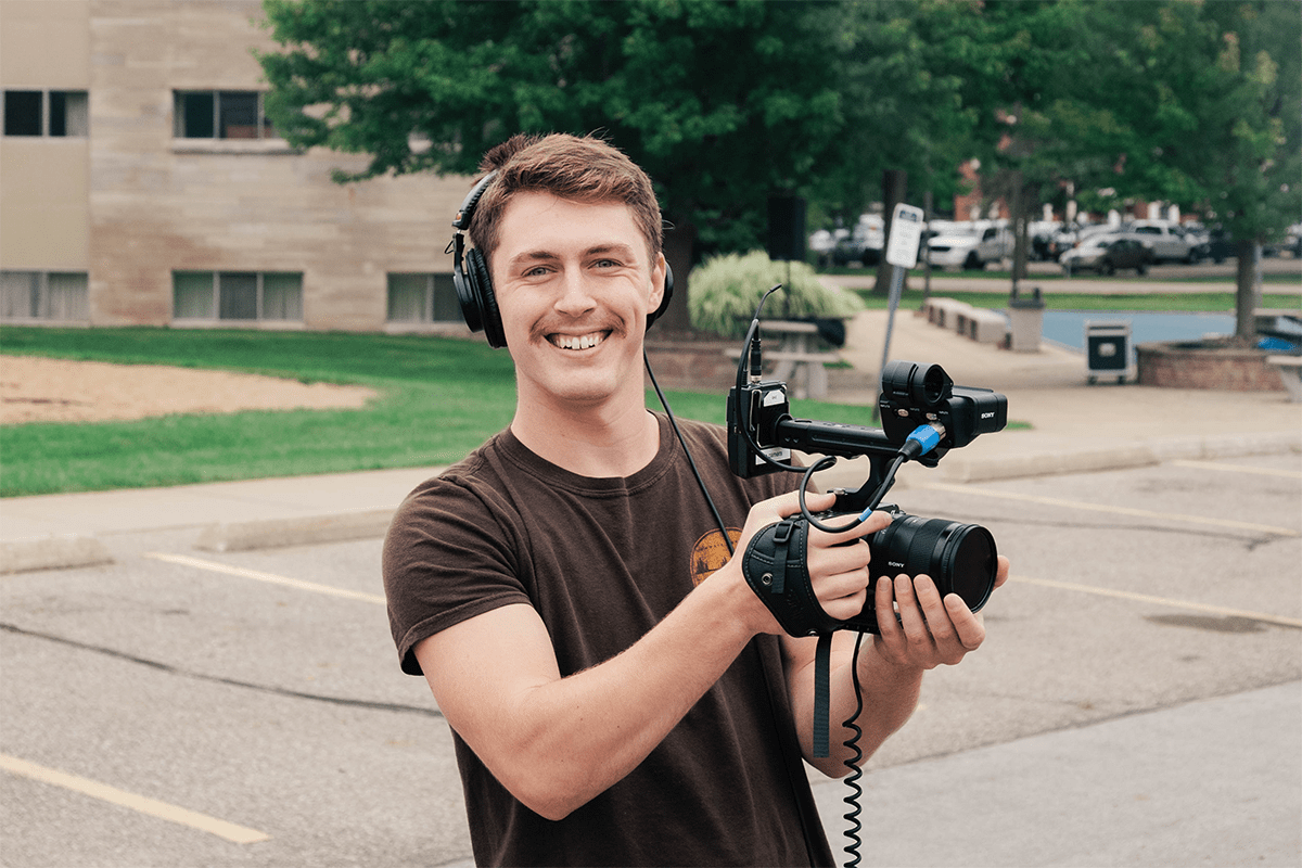 Will Urban holding a film camera smiling for the camera