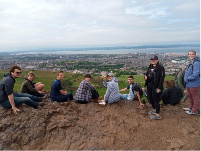 Students sitting down smiling as they overlook the city in England.