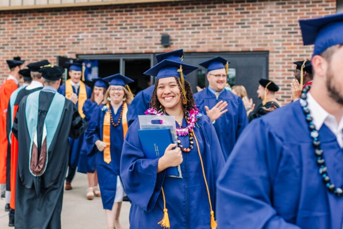 Students walking out of commencement ceremony and smiling.